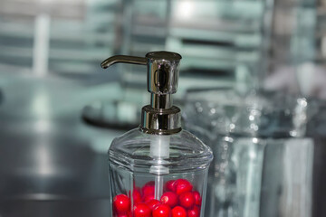 Glass container with pump filled with red fruit