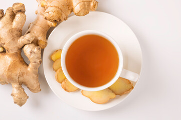 Cup of hot ginger tea with root and slices on white background. Top view
