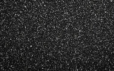 Close-up view of a textured black surface.  Small, speckled particles cover the entire area