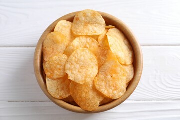 Tasty potato chips in bowl on white wooden table, top view