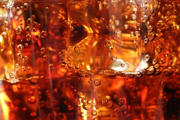 Refreshing cola with ice cubes as background, macro view