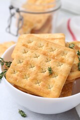 Tasty salty crackers and thyme on white table, closeup