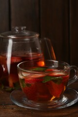 Aromatic fruit tea with strawberries and mint on wooden table, closeup