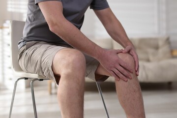 Man suffering from knee pain at home, closeup