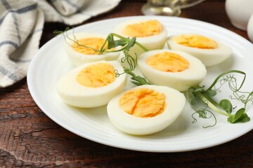 Boiled eggs and microgreens on wooden table, closeup