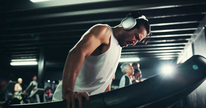 Headphones, sweating and man on treadmill with water in gym for run, late exercise and endurance with fatigue. Cardio, tired runner and machine with drink for thirst, intense and music at night