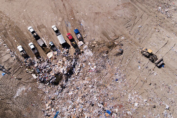 A pile of trash and a few trucks are in the background