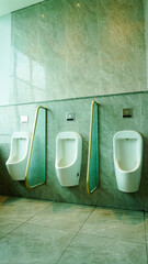 Three urinals in a row with automatic flush sensors and privacy screens, hygienic men’s restroom...