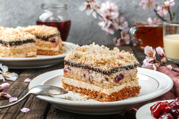 Piece of biscuit cake with cherry and cream on the plate over wooden background with jam and flowers. Sweets, dessert and pastry, homemade cakes, close up, selective focus