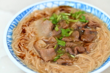 Authentic Taiwanese Mee Sua with pork intestines in close-up, showing broth garnished with cilantro and garlic. This comfort food represents Taiwan's culinary heritage and remains a tourism highlight.