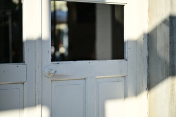 Afternoon sunlight plays across a timber door, casting complex shadows and reflecting distant...