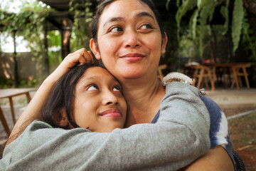 Asian family love and affection between mother and teen daughter, embracing each other tenderly
