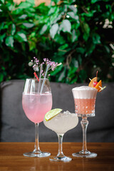 Three cocktails—pink gin and tonic with flowers, a margarita with lime, and a frothy pink drink...