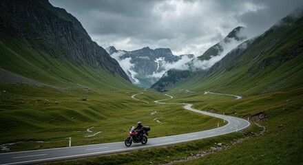Mountain biker riding a winding road.  Vast valley, alpine scenery