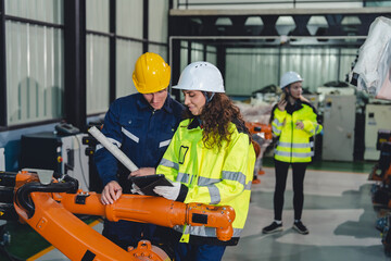 Industrial engineers collaborate in a high-tech factory environment, inspecting robotic machinery...