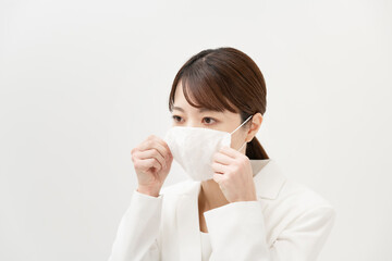 マスクを着ける白いスーツ姿の女性