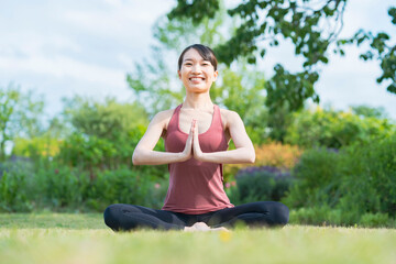 緑あふれる公園でヨガをする若い女性