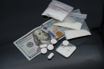Narcotics addiction. White pills ,100 dollar bill and Plastic bag of powdered mephedrone drugs.