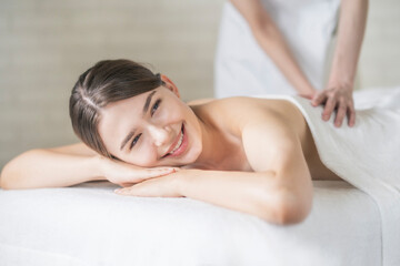 Obraz premium 明るい雰囲気のエステサロンでマッサージを受ける若い女性