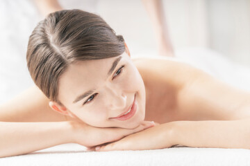 Fototapeta premium 明るい雰囲気のエステサロンでマッサージを受ける若い女性