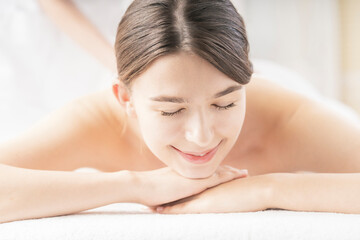 Obraz premium 明るい雰囲気のエステサロンでマッサージを受ける若い女性