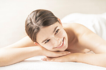 Obraz premium 明るい雰囲気のエステサロンでベッドに横になる若い女性