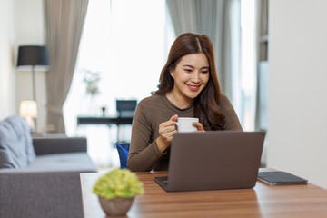 Image of young asian happy cheerful cute beautiful business Asian woman sit indoors in home office using laptop computer work in a video conference on line  © David