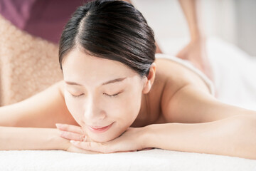 Obraz premium 明るい雰囲気のエステサロンでマッサージを受ける若い女性