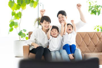 手をあげて喜ぶ親子・テレビ観戦イメージ
