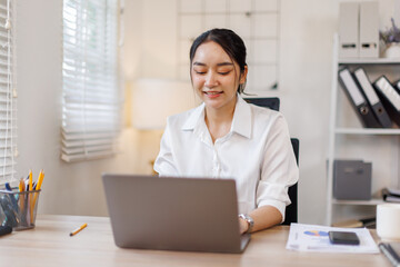 Business Asian woman using calculator and laptop for doing math finance on an office desk, tax, report, accounting, statistics, and analytical research concept
