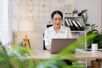 Business Asian woman using calculator and laptop for doing math finance on an office desk, tax, report, accounting, statistics, and analytical research concept
