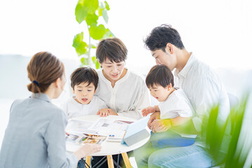 スーツ姿の女性からインテリアの説明を受ける家族