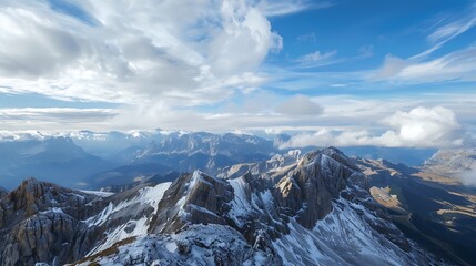 Obraz premium Aerial View Of Snowy Mountain Peaks Under A Blue Sky With Fluffy Clouds