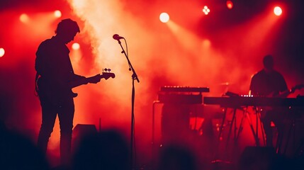 Obraz premium Silhouetted musicians bathed in crimson light energizing stage performance