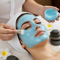 Woman receiving a facial mask treatment at a spa with stones and flower