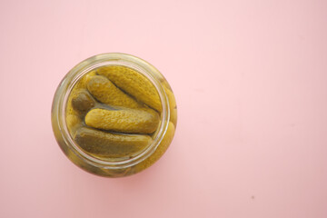 Pickles in a jar on pink surface