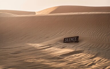 Sign reading 'Silence' in a tranquil desert setting.