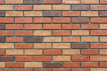 Obraz premium A brick wall with varying shades of red, brown, and orange brick pattern design