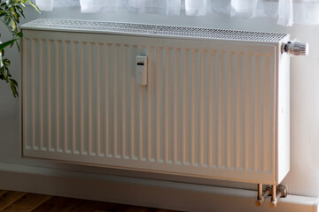 Heating with panel radiator and heat cost allocator and thermostat on the wall. A wireless heat meter on white radiator. Heating of houses in the cold season