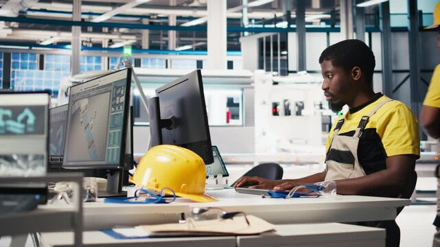 Black worker programming robotic assembly line in solar cell factory, working with high tech software for automation. Male engineer testing photovoltaic system, machinery. Camera B.