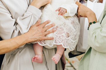 ドレスを着た赤ちゃんを大人たちが囲む