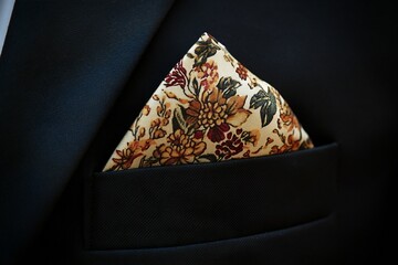 A silk pocket square with floral print, neatly folded and placed in a black suit pocket, created by ai