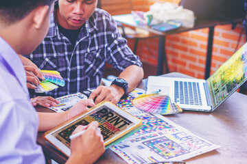 Team graphic designer checking print quality of media graphics proof print and color guides in...
