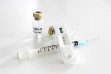 Vial of Covid-19 vaccine, 1 ml plastic syringe with needle and Positive test result of Covid-19 antigen test kit isolated on the white background