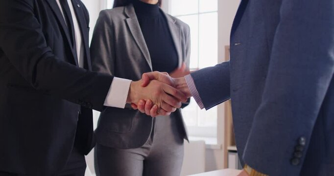 Happy business people in formal suit making a deal shaking hands with partners standing at desk in office during meeting. Company employees applauding colleagues. 4k video. Slow motion video.