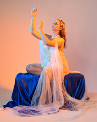 Fantasy studio portrait of a red-haired mermaid faery model wearing a white pearl gown, fairytale...