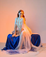 Fantasy studio portrait of a red-haired mermaid faery model wearing a white pearl gown, fairytale...