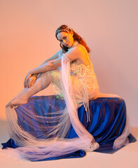 Fantasy studio portrait of a red-haired mermaid faery model wearing a white pearl gown, fairytale...