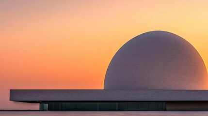 Obraz premium A modern concrete building against an orange and yellow sunset sky