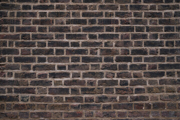 Close up of a weathered brick wall with visible texture and mortar lines in a traditional pattern.